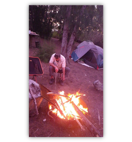 A person sitting next to a campfire

Description automatically generated