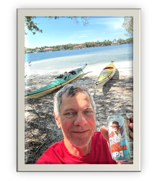 A person holding a can of beer on a beach

Description automatically generated